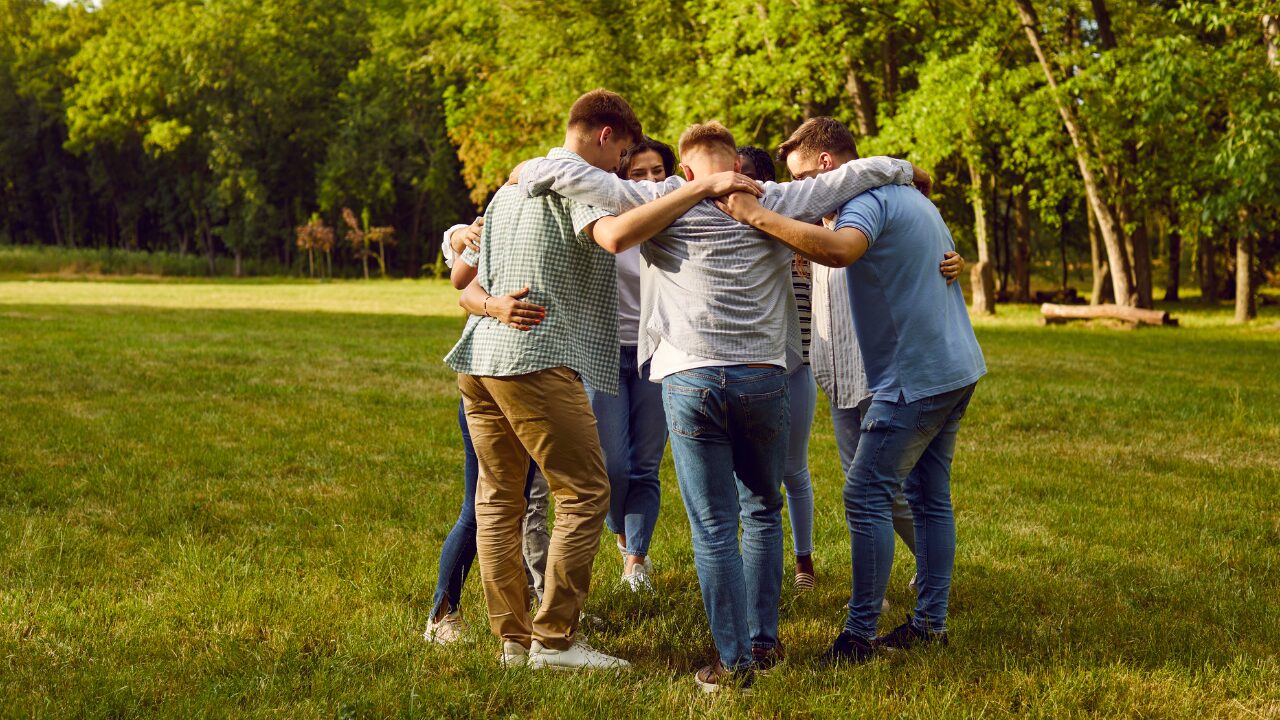 Diverse group huddling on green lawn